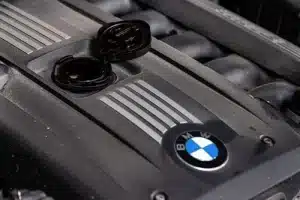 BMW car engine with emblem and open engine filler neck for oil change.