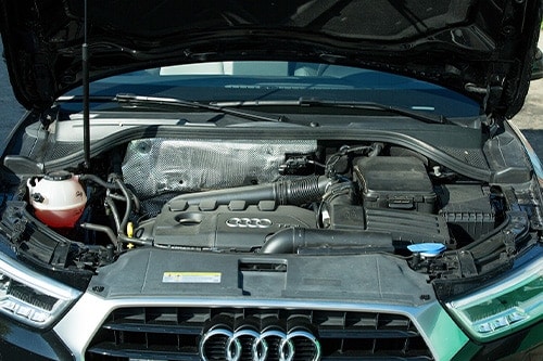 Close-up of the engine and contents of an Audi Q3 under the hood.